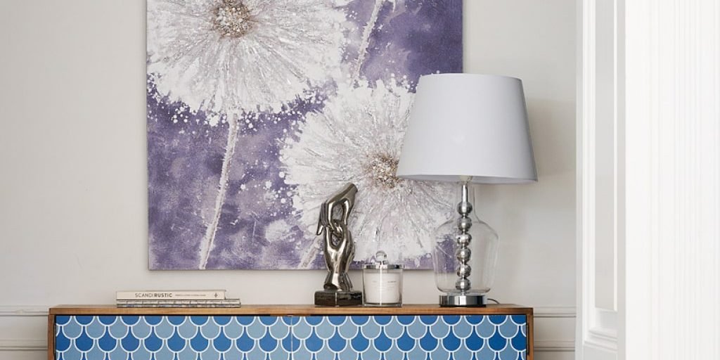 dekoracje do salonu - kompozycja z plakatu, figurki i lampy stołowej